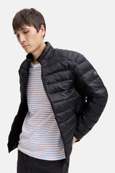 Veste de pluie noire de JACK & JONES, portée sur un t-shirt à rayures horizontales.