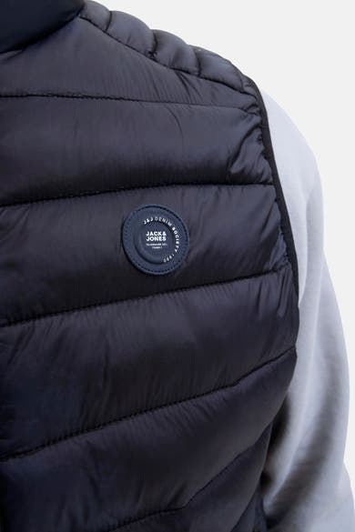 Veste sans manches noire de JACK & JONES, à motif matelassé, avec un écusson rond sur la poitrine.
