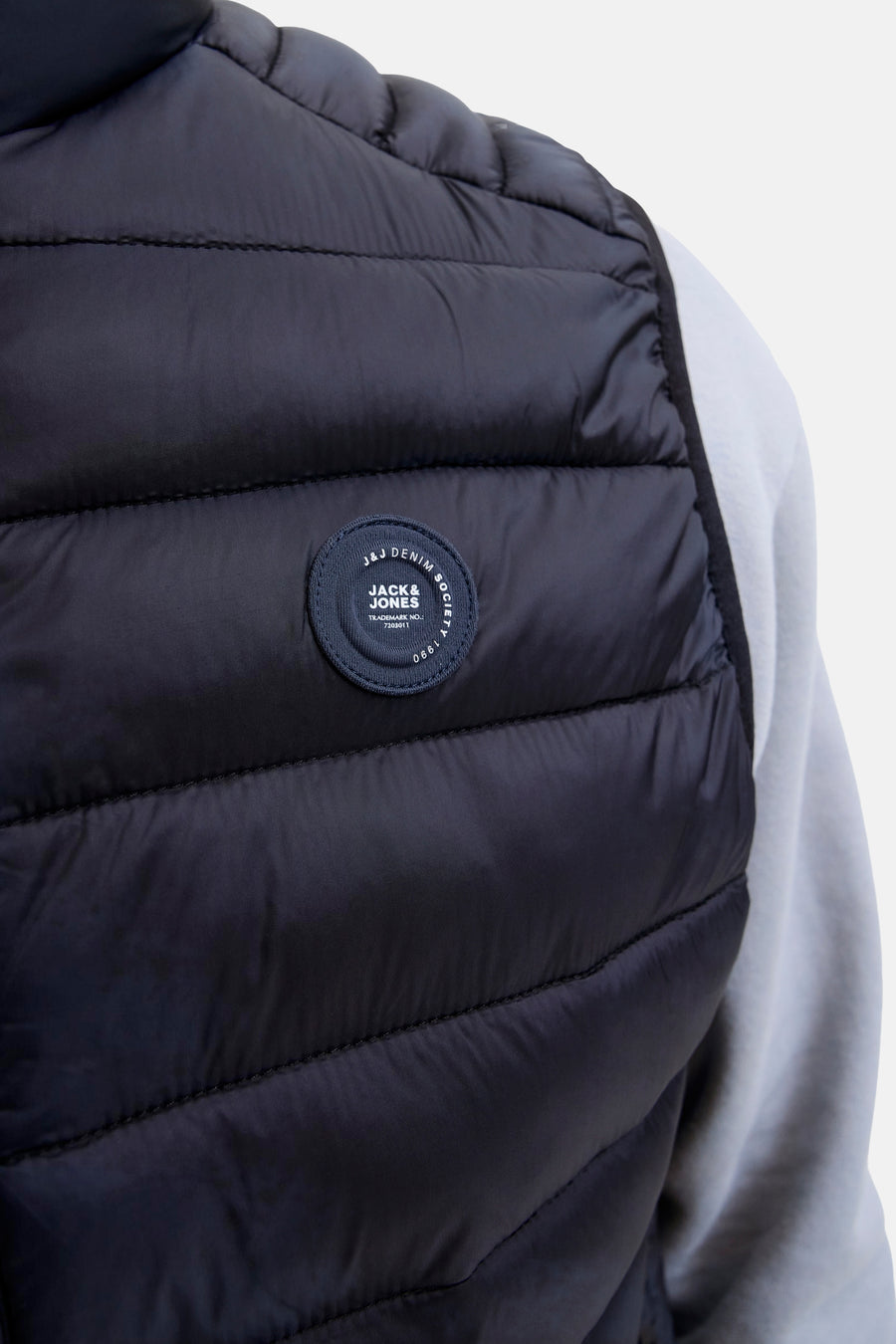 Veste sans manches noire de JACK & JONES, à motif matelassé, avec un écusson rond sur la poitrine.

