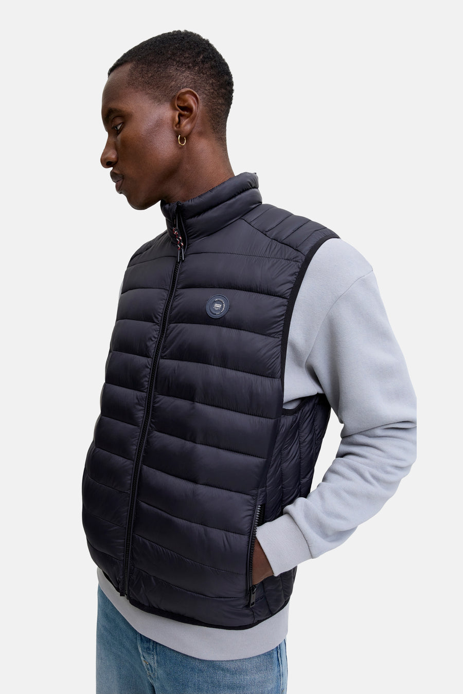 Veste sans manches noire de JACK & JONES, avec fermeture éclair et une personne portant des boucles d'oreilles.
