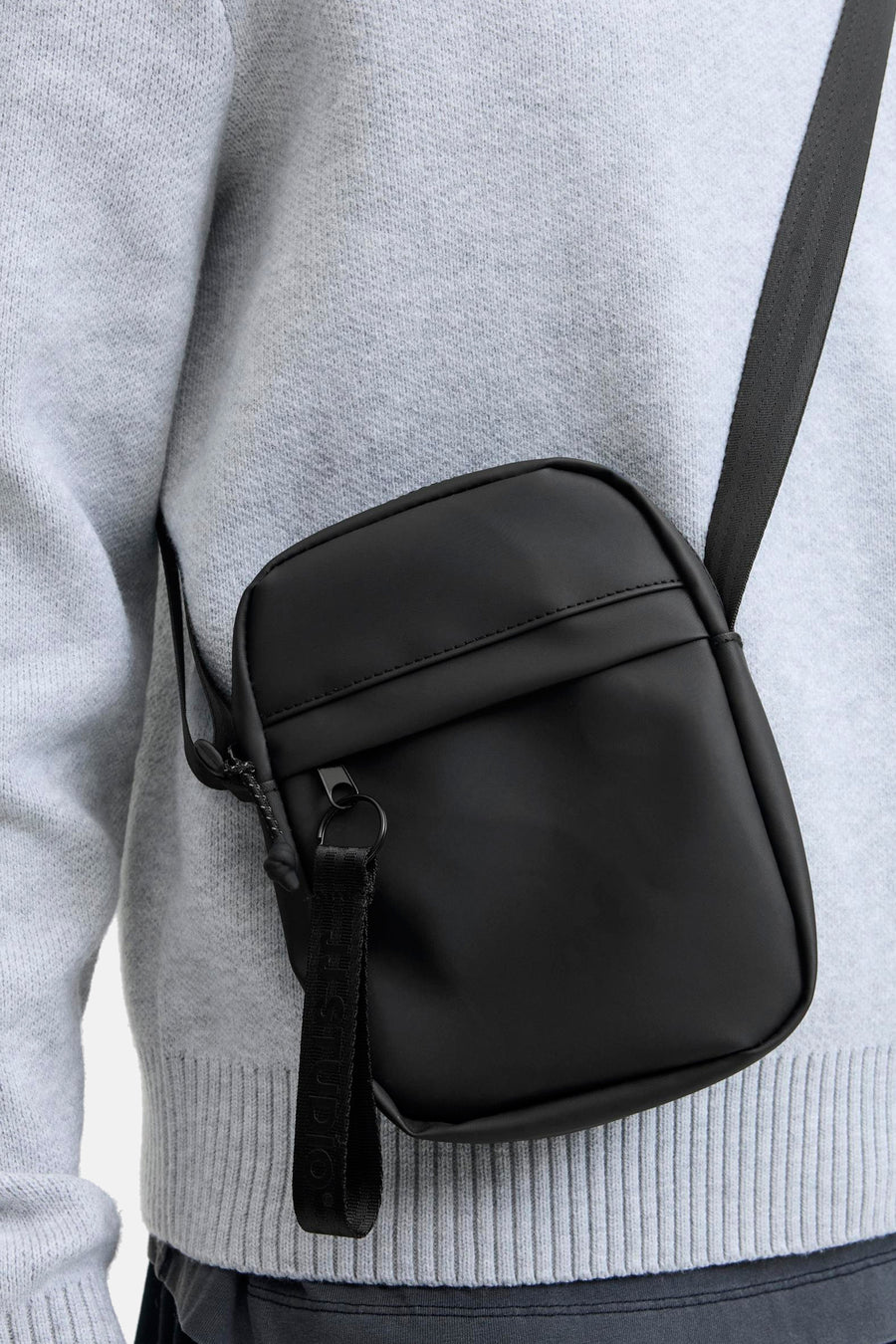 Zwarte schoudertas ACCESSORIES BY JACK & JONES, gedragen over een grijze gebreide trui.