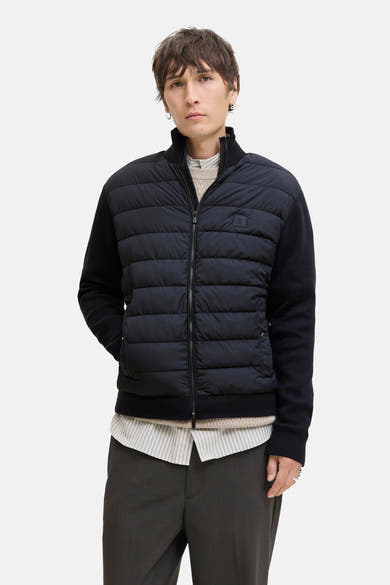 Gewatteerd blauw jack van PREMIUM by JACK & JONES, met gebreide mouwen en ritssluiting over gestreept overhemd en donkere broek.