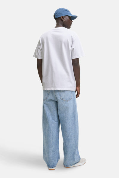 T-shirt à manches courtes blanc de JACK & JONES, porté avec un jean ample et une casquette bleu marine.