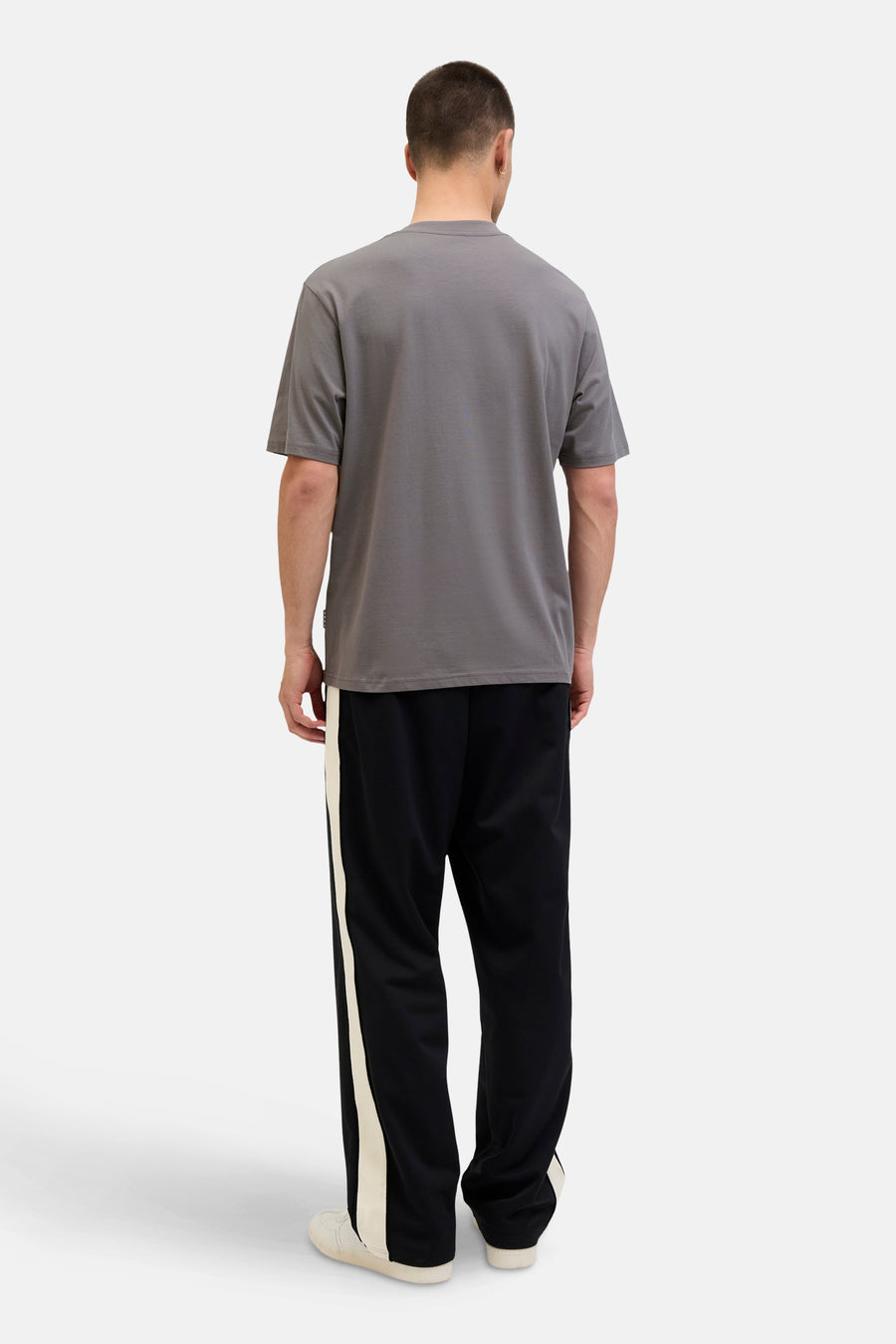 Grijze T-shirt met korte mouwen van JACK & JONES, gedragen met een zwarte joggingbroek met crèmekleurige strepen.