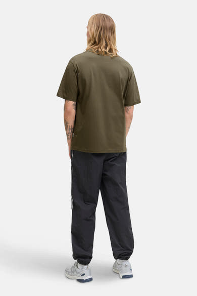 Olijfgroen T-shirt met korte mouwen van Jack & Jones, gedragen met een zwarte broek en sneakers.