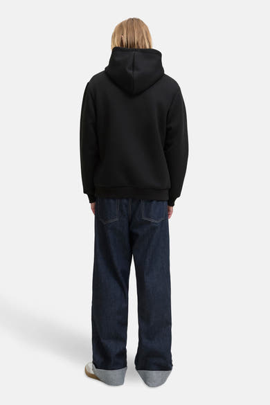 Zwarte hoodie van JACK & JONES, gedragen met een wijde jeans en sneakers.