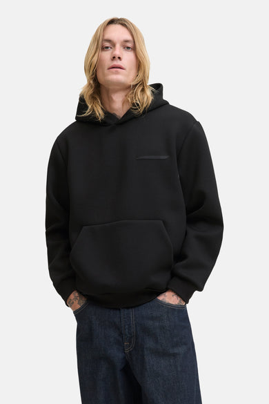 Sweat à capuche noir de JACK & JONES, avec une poche kangourou et un patch décoratif sur la poitrine.