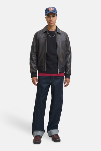 Pull à col rond noir par ORIGINALS BY JACK & JONES, porté avec une veste en cuir marron, un jean ample et des chaussures marron.