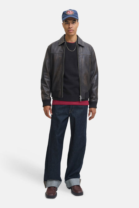 Pull à col rond noir par ORIGINALS BY JACK & JONES, porté avec une veste en cuir marron, un jean ample et des chaussures marron.