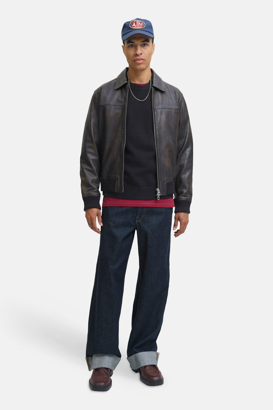 Pull à col rond noir par ORIGINALS BY JACK & JONES, porté avec une veste en cuir marron, un jean ample et des chaussures marron.