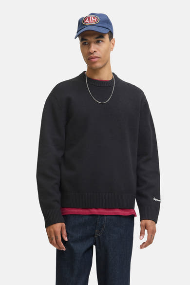 Zwarte rondehals trui van ORIGINALS BY JACK & JONES, gedragen met een rood T-shirt en wijde spijkerbroek, achtergezicht.