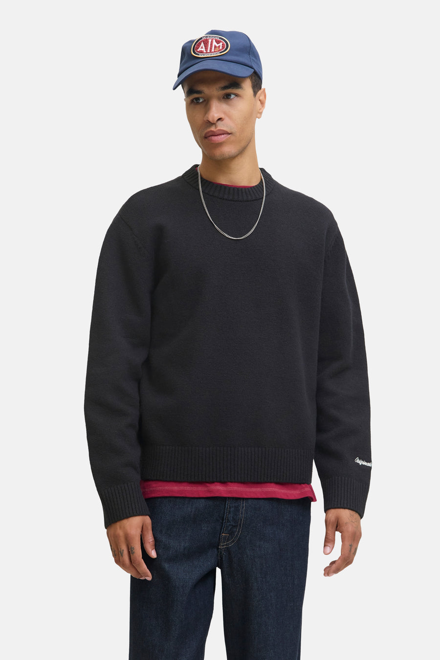 Zwarte rondehals trui van ORIGINALS BY JACK & JONES, gedragen met een rood T-shirt en wijde spijkerbroek, achtergezicht.