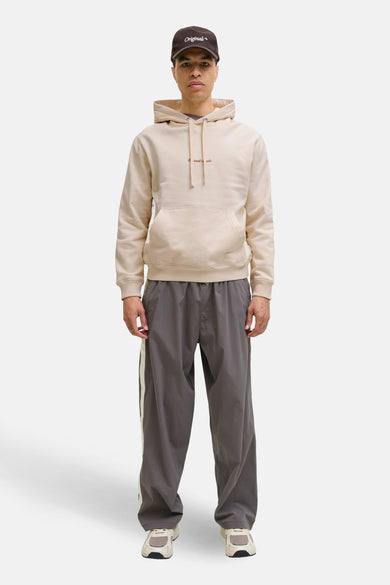 Sweat à capuche beige par PREMIUM by JACK & JONES, avec une poche kangourou devant, porté avec un pantalon de survêtement gris.