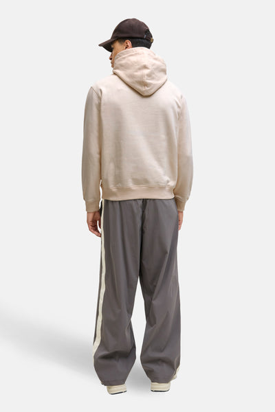 Sweat à capuche beige de PREMIUM by JACK & JONES, porté avec un pantalon gris à rayures sur le côté.