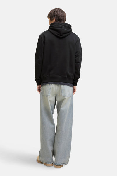 Zwarte hoodie van PREMIUM by JACK & JONES, achterkant, gedragen met een wijde jeans en beige enkellaarsjes.