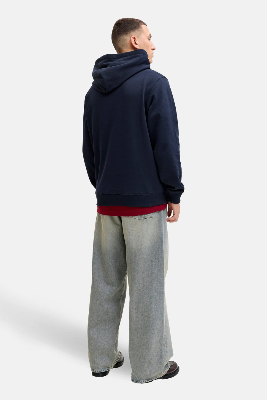 Blauwe hoodie van PREMIUM by JACK & JONES, gedragen met een rood T-shirt en een grijze wijde jeans.
