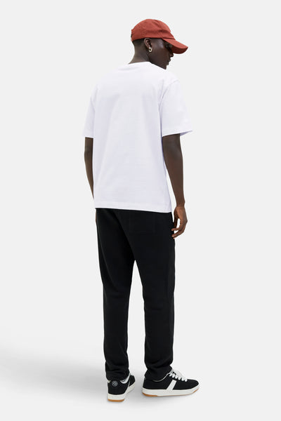 Wit T-shirt met korte mouwen van ORIGINALS BY JACK & JONES, gedragen met een zwarte joggingbroek en sportschoenen.