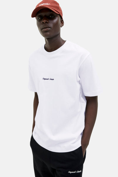T-shirt blanc à manches courtes d’ORIGINALS BY JACK & JONES avec un pantalon noir et une casquette brique.

