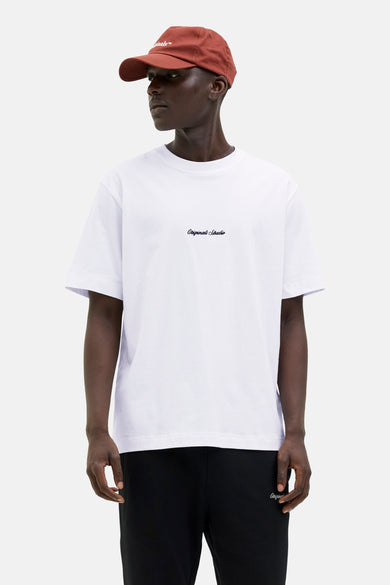 Wit T-shirt met korte mouwen van Originals by Jack & Jones, gedragen met een zwarte broek en een roestkleurige pet.