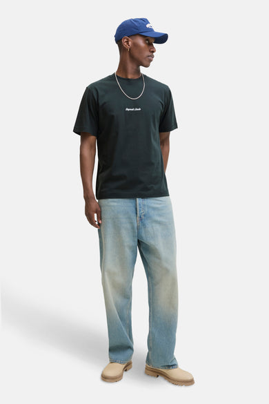Groen T-shirt met korte mouwen, van Originals by Jack & Jones, gedragen met een wijde blauwe jeans, een zilveren ketting en een marineblauwe pet.