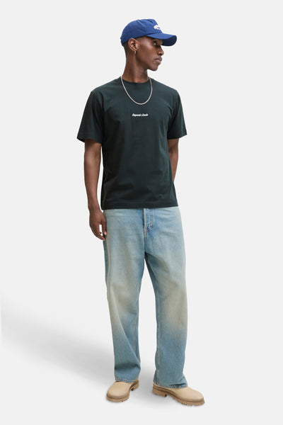 Groen T-shirt met korte mouwen, van Originals by Jack & Jones, gedragen met een wijde blauwe jeans, een zilveren ketting en een marineblauwe pet.
