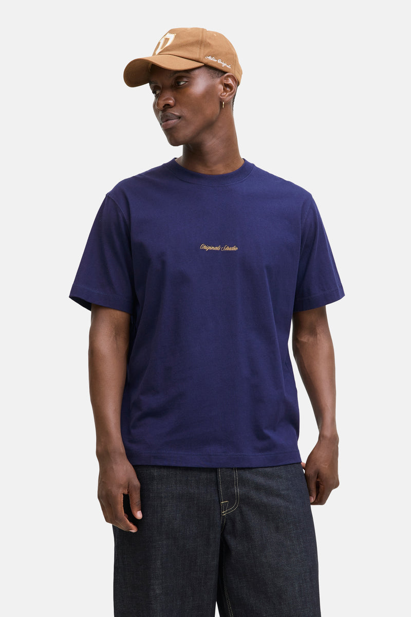 Blauw T-shirt met korte mouwen van ORIGINALS BY JACK & JONES, gedragen met een beige pet en een spijkerbroek.