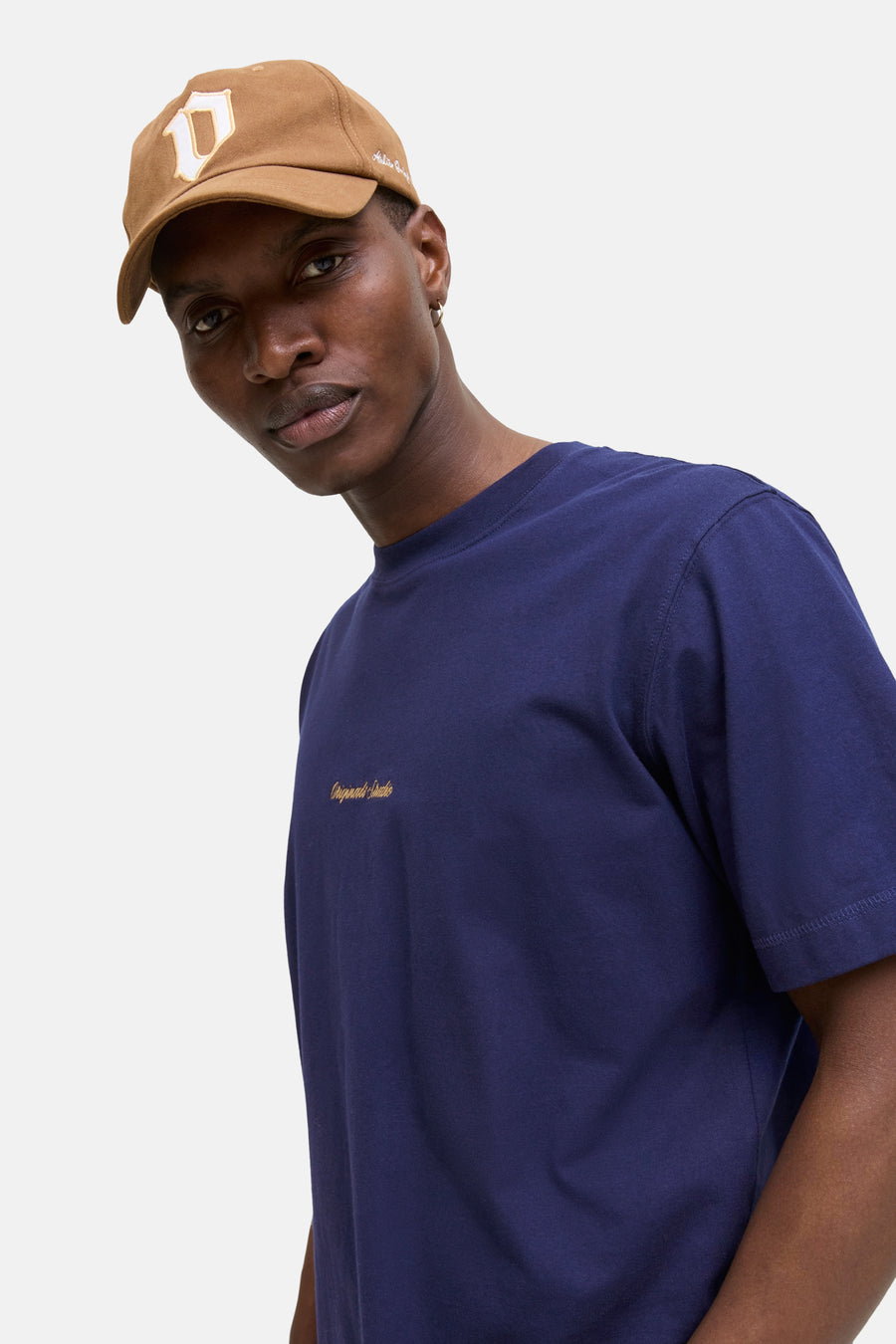 Blauw T-shirt met korte mouwen van Originals by Jack & Jones, met geborduurd logo op de borst, gedragen met een bruine pet.