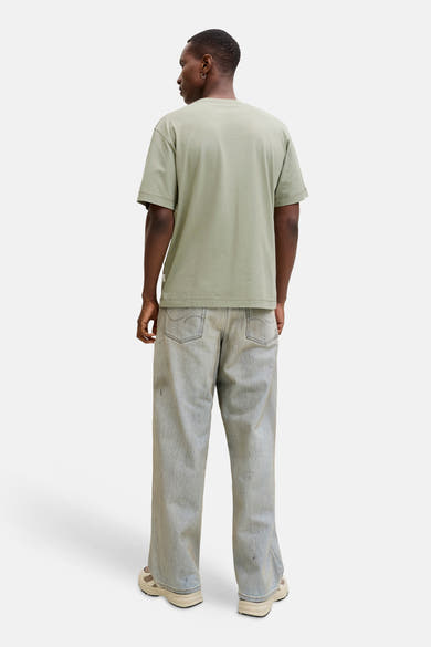 T-shirt à manches courtes vert de ORIGINALS BY JACK & JONES, porté avec un jean ample délavé et des baskets beiges.