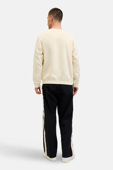 Ecru ronde hals sweatshirt van ORIGINALS BY JACK & JONES, gedragen met een zwarte broek met witte strepen, achterzijde.