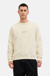 Ecru ronde hals sweatshirt van ORIGINALS BY JACK & JONES, met geborduurd logo, gedragen met een zwarte broek.