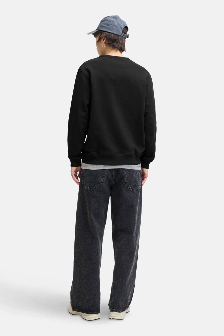 Zwarte rondehals sweatshirt van ORIGINALS BY JACK & JONES, gedragen met een wijde zwarte jeans en een lichtblauwe pet.