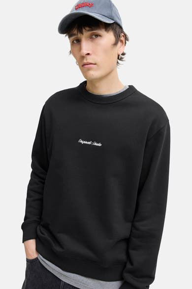 Zwarte rondehals sweatshirt van ORIGINALS BY JACK & JONES, gedragen met een grijs T-shirt en een lichtblauwe pet.