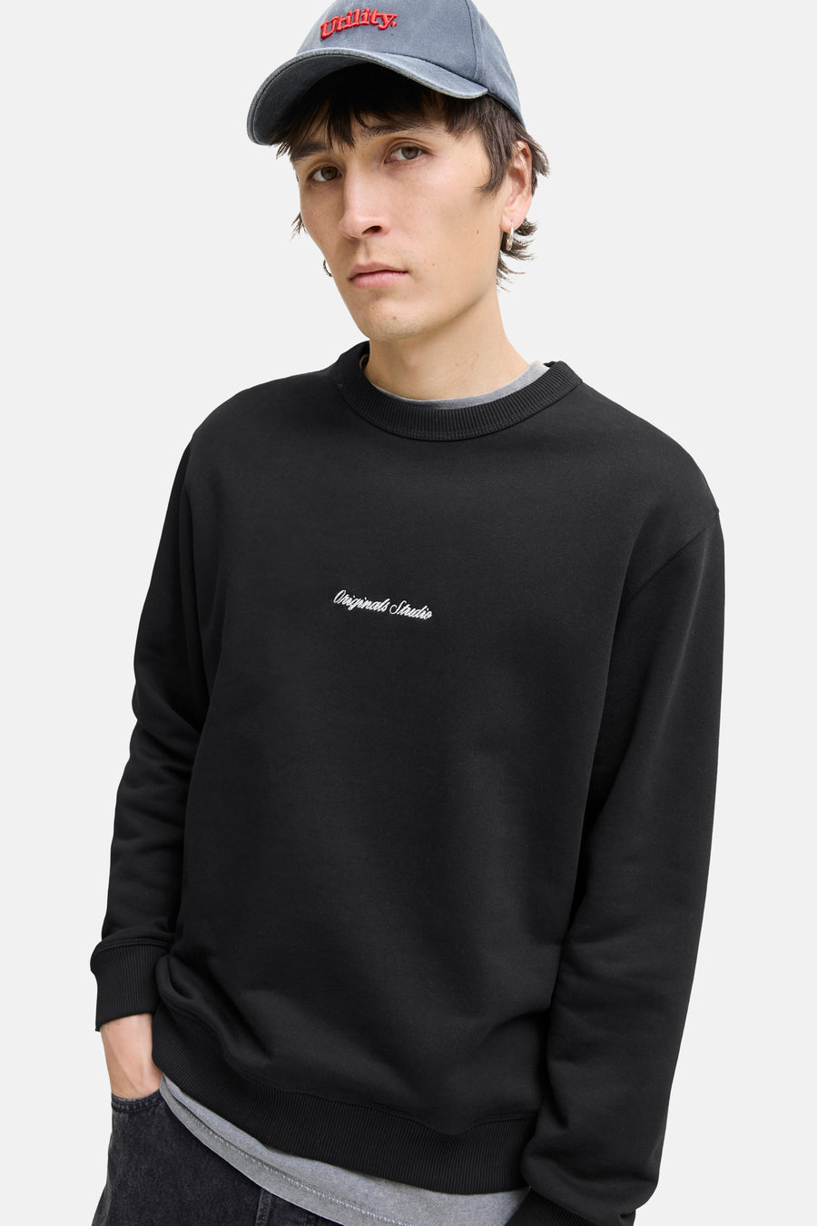 Zwarte rondehals sweatshirt van ORIGINALS BY JACK & JONES, gedragen met een grijs T-shirt en een lichtblauwe pet.