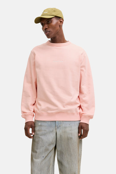 Sweat rose Originals by Jack & Jones, porté avec un pantalon ample délavé et une casquette olive.