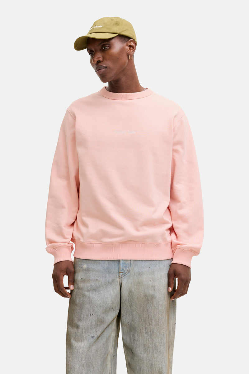 Sweat rose Originals by Jack & Jones, porté avec un pantalon ample délavé et une casquette olive.