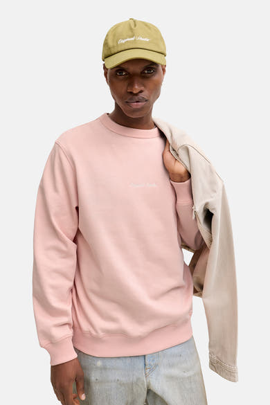 Roze sweatshirt van ORIGINALS BY JACK & JONES, gedragen met een olijfgroene pet en een beige jas.