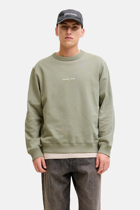 Groene trui met ronde hals van Originals by Jack & Jones, gedragen met een donkere jeans en een pet.