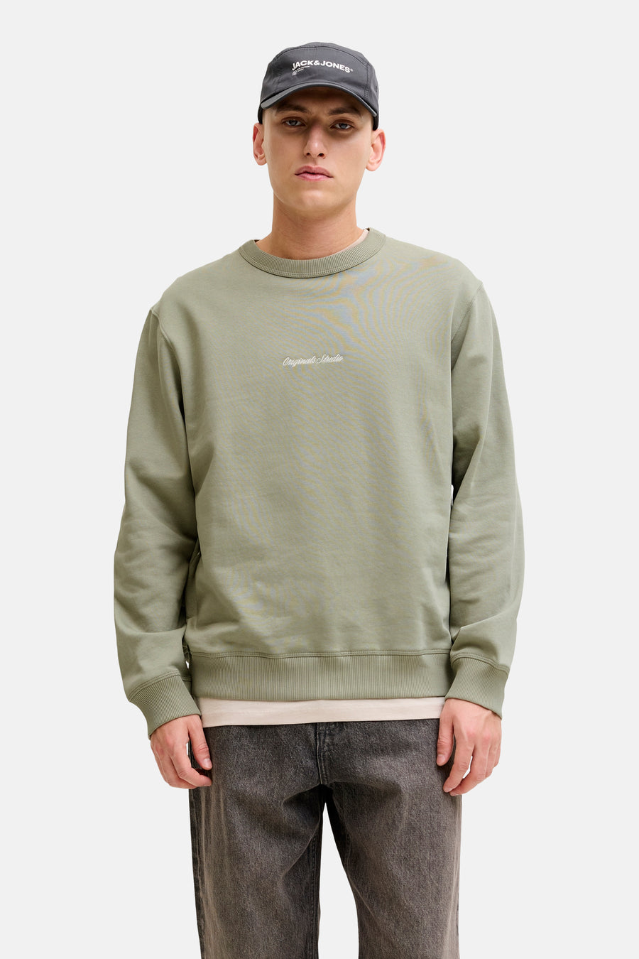 Groene trui met ronde hals van Originals by Jack & Jones, gedragen met een donkere jeans en een pet.