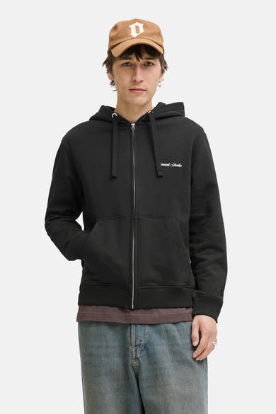 Zwarte (bodywarmer) sweater van PREMIUM by JACK & JONES, gedragen over een bruin T-shirt en een blauwe jeans.