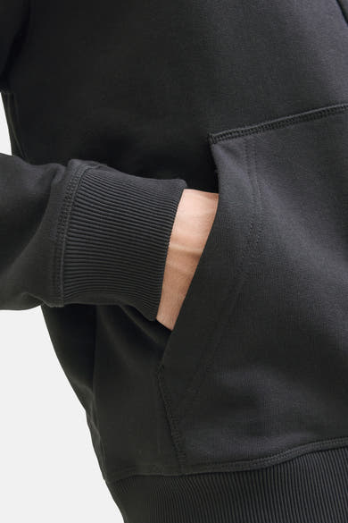 Zwarte sweater van PREMIUM by JACK & JONES, met een hand in de kangoeroezak.