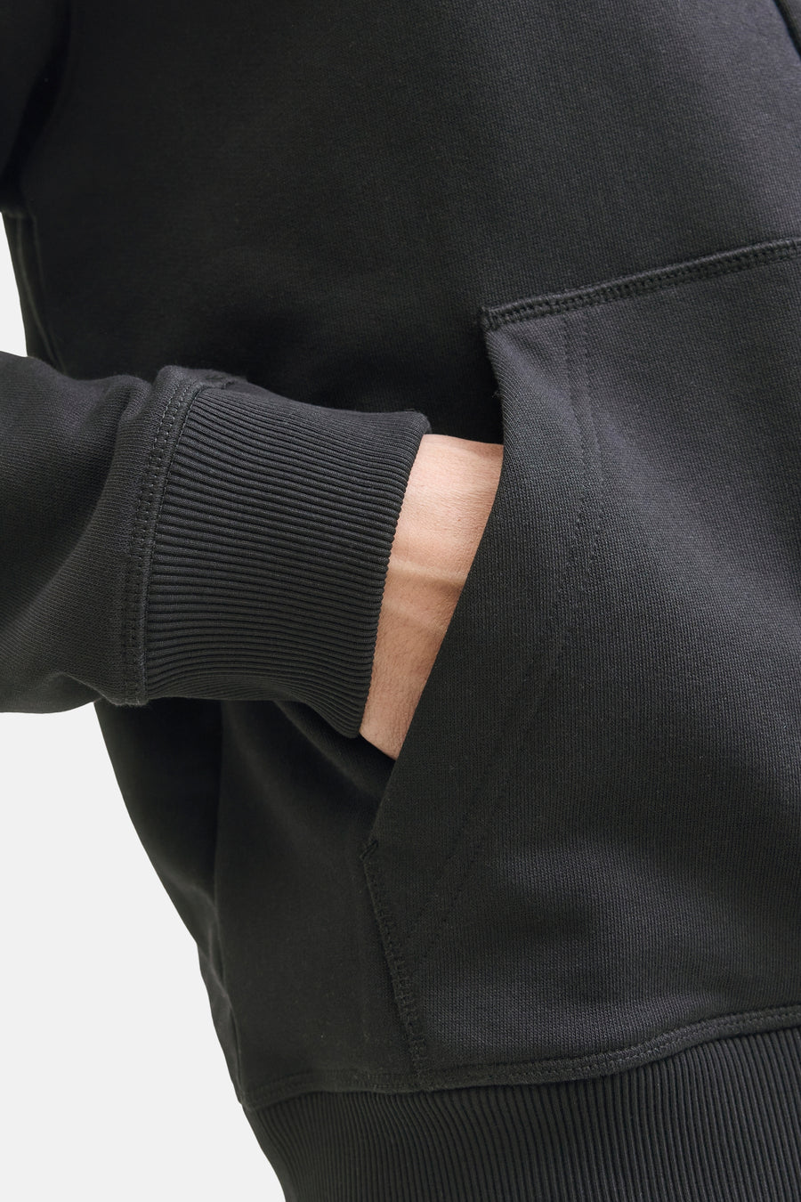 Zwarte sweater van PREMIUM by JACK & JONES, met een hand in de kangoeroezak.