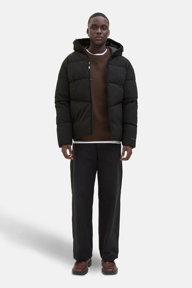 Zwarte regenjas van ORIGINALS BY JACK & JONES, gedragen over een bruine trui en een zwarte broek.