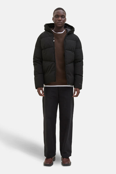 Zwarte regenjas van ORIGINALS BY JACK & JONES, gedragen over een bruine trui en een zwarte broek.