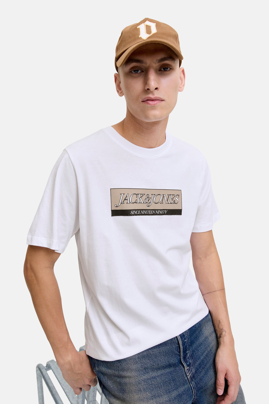 Wit T-shirt met korte mouwen van ORIGINALS BY JACK & JONES, met opgedrukte logo op de voorkant, gedragen met een blauwe jeans en een bruine pet