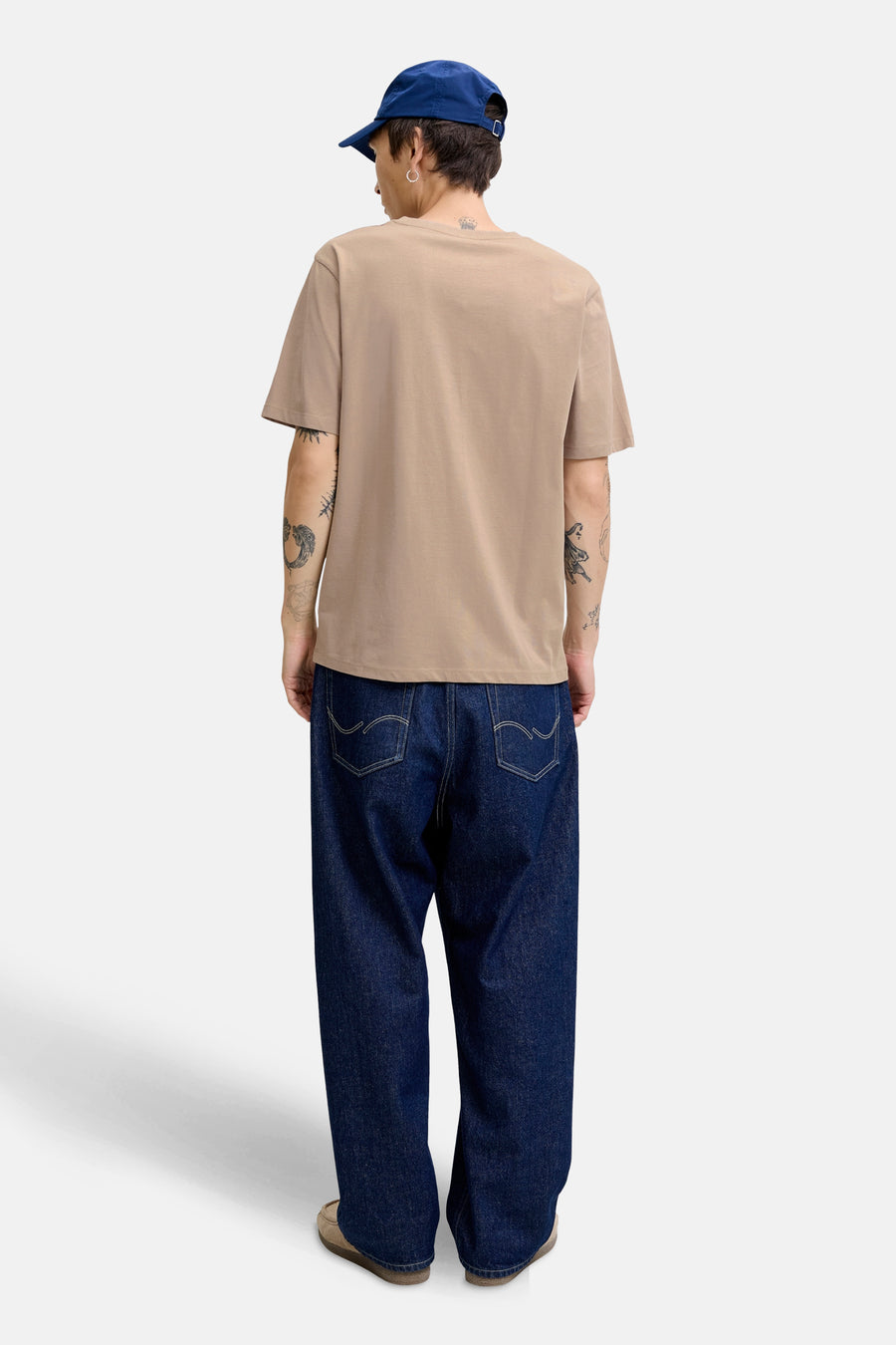 Beige T-shirt met korte mouwen van ORIGINALS BY JACK & JONES, gedragen met een wijde jeans en een blauwe pet.