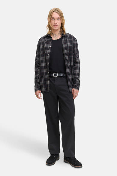 Chino noir JACK & JONES JEANS INTELLIGENCE porté avec une chemise à carreaux et des chaussures bateau.
