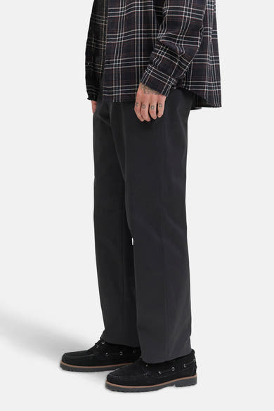 Zwarte chino van JACK & JONES JEANS INTELLIGENCE, gedragen met een geruit overhemd en bootschoenen.