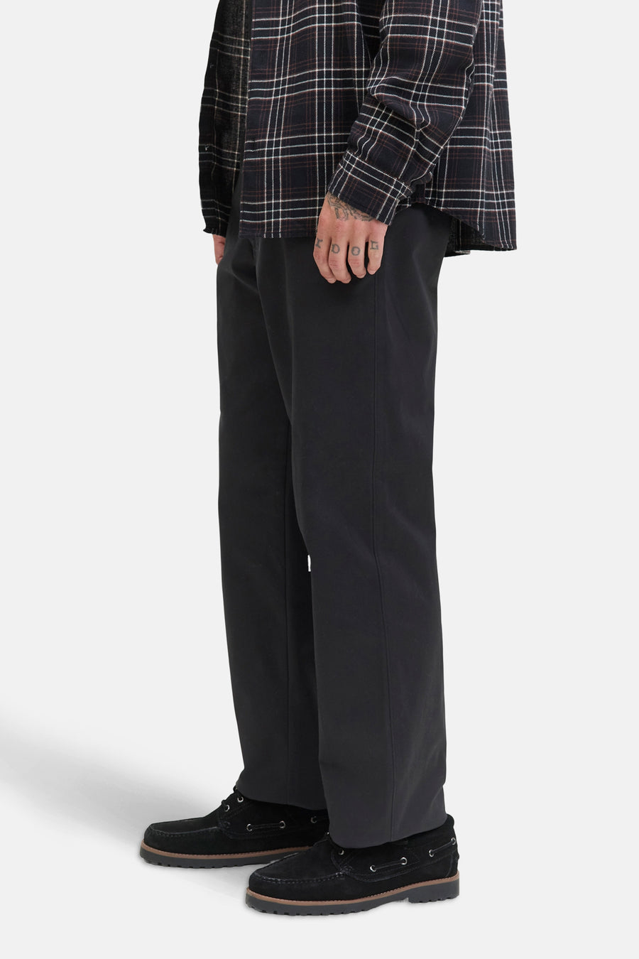 Zwarte chino van JACK & JONES JEANS INTELLIGENCE, gedragen met een geruit overhemd en bootschoenen.