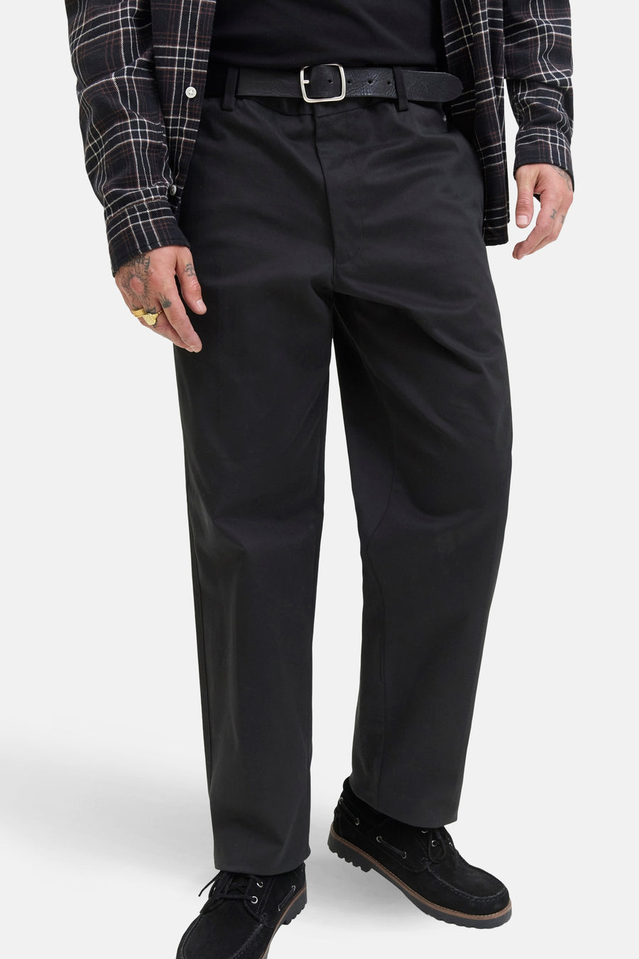 Zwarte chino van JACK & JONES JEANS INTELLIGENCE, gedragen met een zwarte riem en een geruit overhemd.