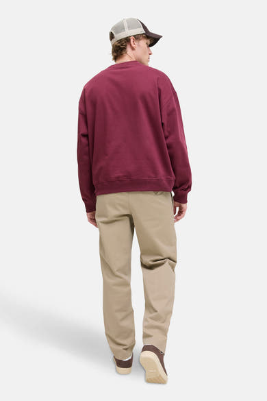 Pantalon chino beige de JACK & JONES JEANS INTELLIGENCE porté avec un sweatshirt bordeaux et une casquette.